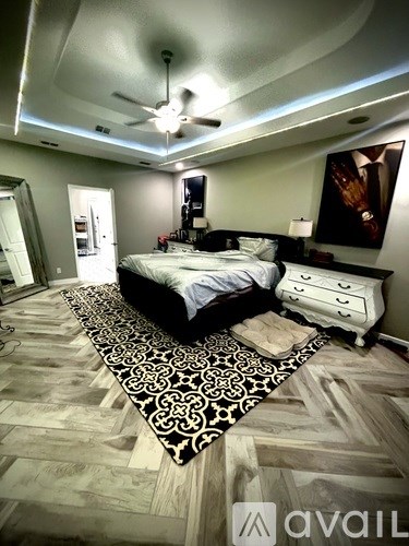 A bedroom with a bed, dresser, and a ceiling fan.