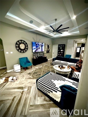 A living room with a striped rug and a ceiling fan.