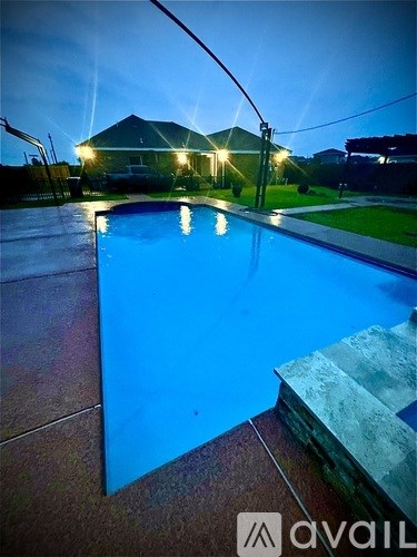 A pool at night with lights on in the background.