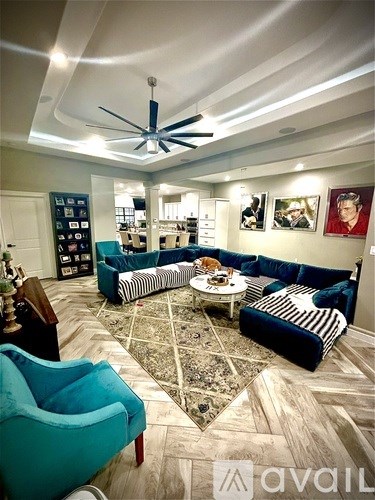 A living room with a blue couch and a ceiling fan.