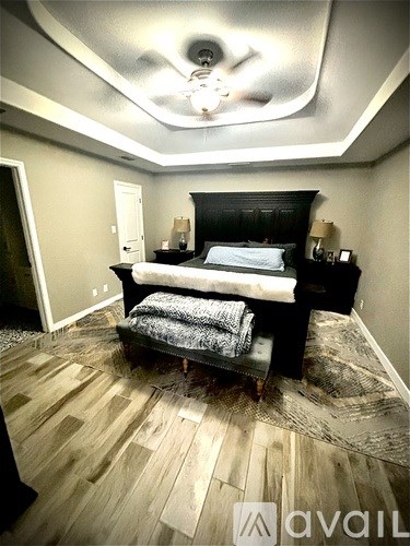 A bedroom with a bed, nightstands, and a ceiling fan.