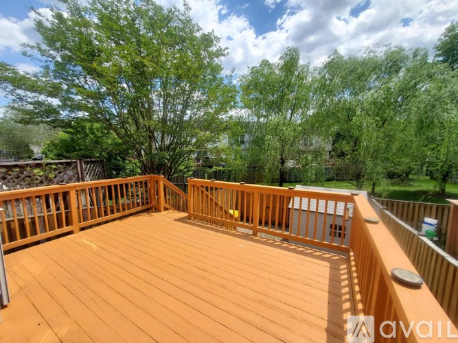 A wooden deck with a railing and a tree in the background.