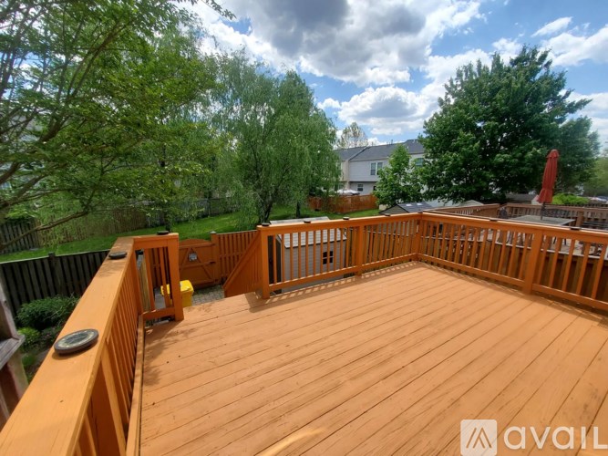 A wooden deck with a railing and a tree in the background.