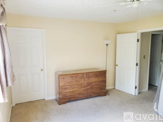 A room with a wooden chest of drawers and a white door.