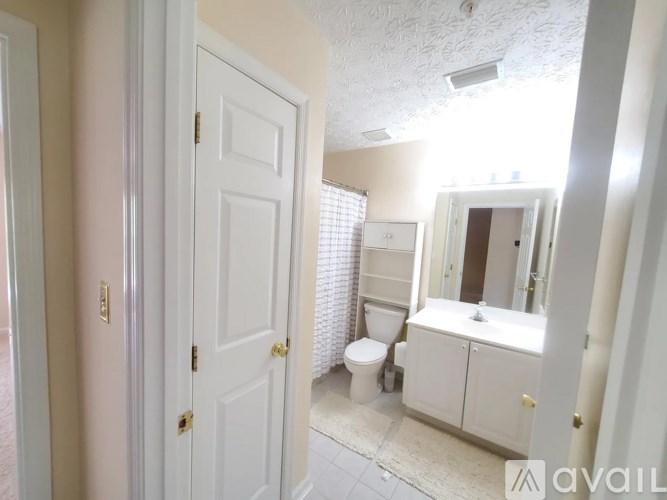 A bathroom with a toilet, sink, and mirror.