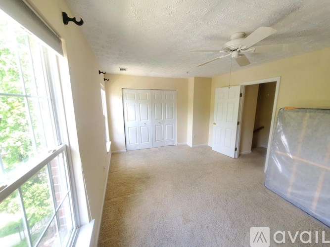 A room with a fan, carpet, and a window.