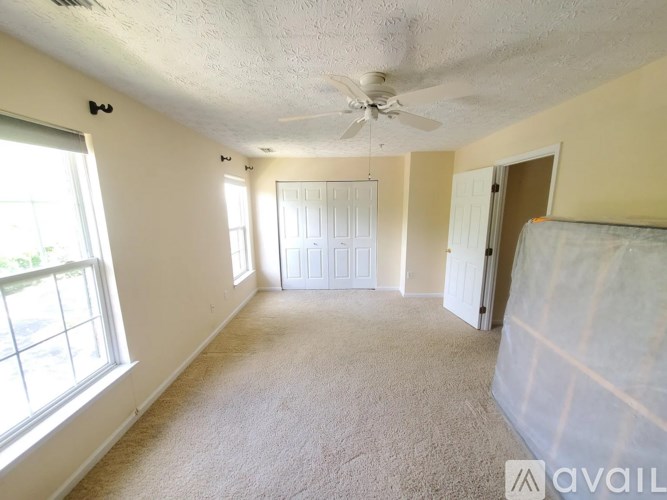 A room with a carpeted floor, a ceiling fan, and a window with blinds.