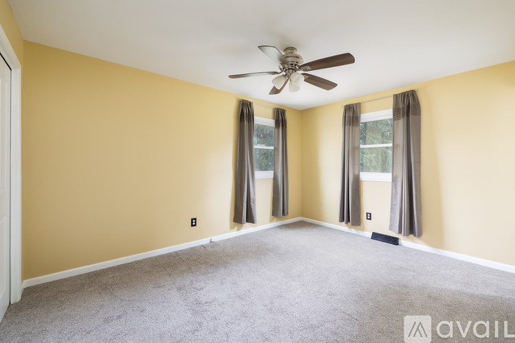 A room with a ceiling fan and carpeted floor.