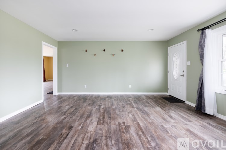 A room with wooden flooring and white walls.