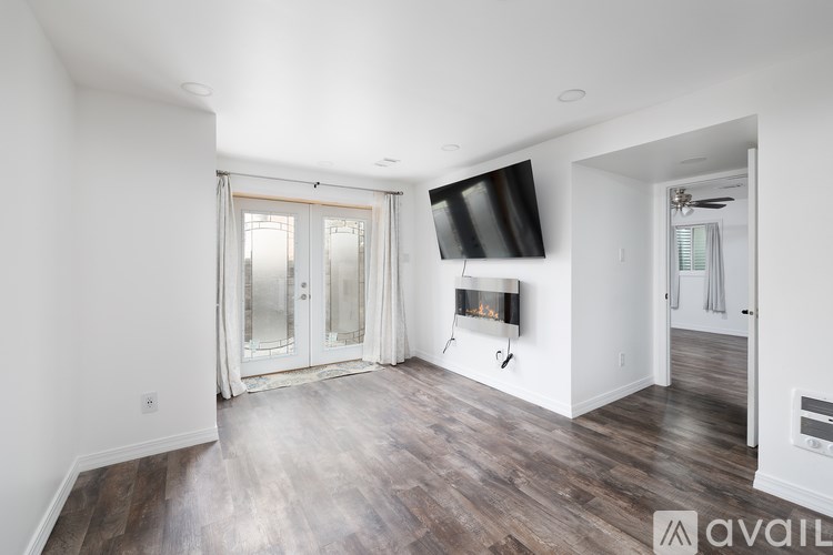 A spacious living room with wood flooring and a television mounted on the wall.