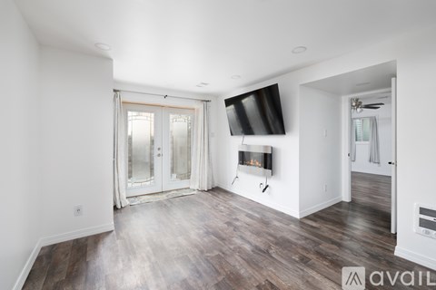 A spacious living room with wood flooring and a television mounted on the wall.