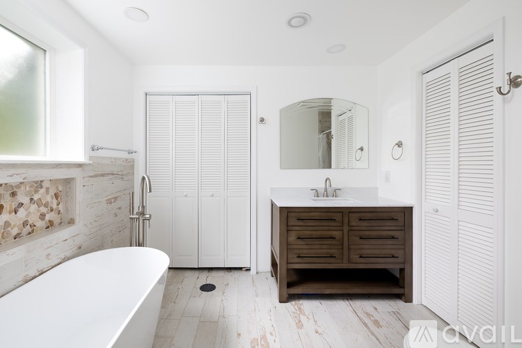 A white bathroom with a tub, sink, and mirror.