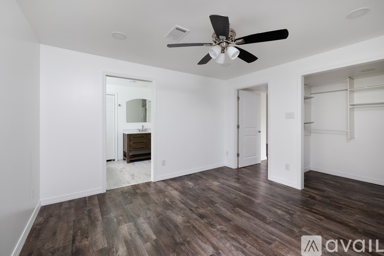 A room with a ceiling fan and wooden flooring.