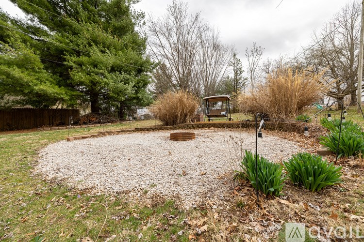 A garden with a gravel circle and a wooden bench.