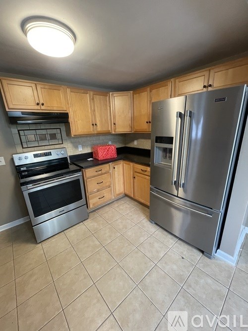 A kitchen with wooden cabinets and a stainless steel refrigerator.