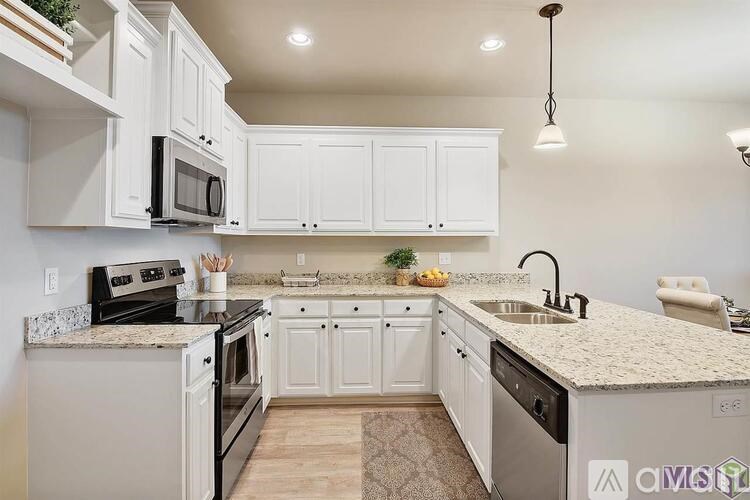 A kitchen with white cabinets and a granite countertop.
