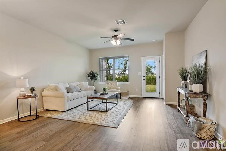 A living room with a white couch, a glass coffee table, and a ceiling fan.