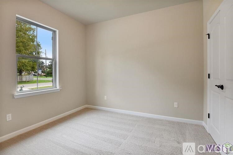 A room with a carpeted floor, a window, and a door.