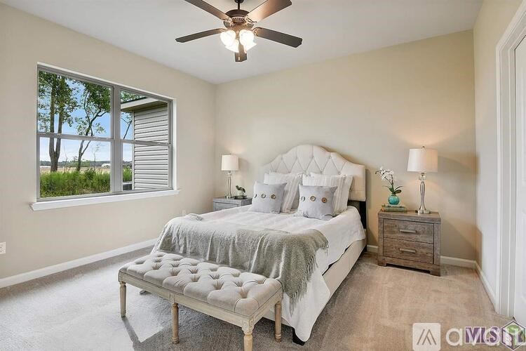 A bedroom with a large bed, a bench, and a ceiling fan.