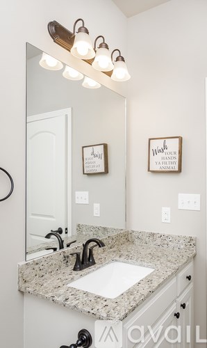 A bathroom with a granite counter top and a mirror above it.