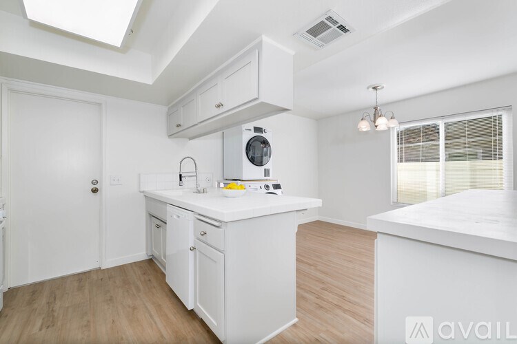 A kitchen with white cabinets and a wooden floor.