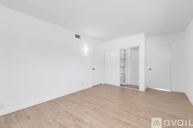 A spacious room with wooden flooring and white walls.
