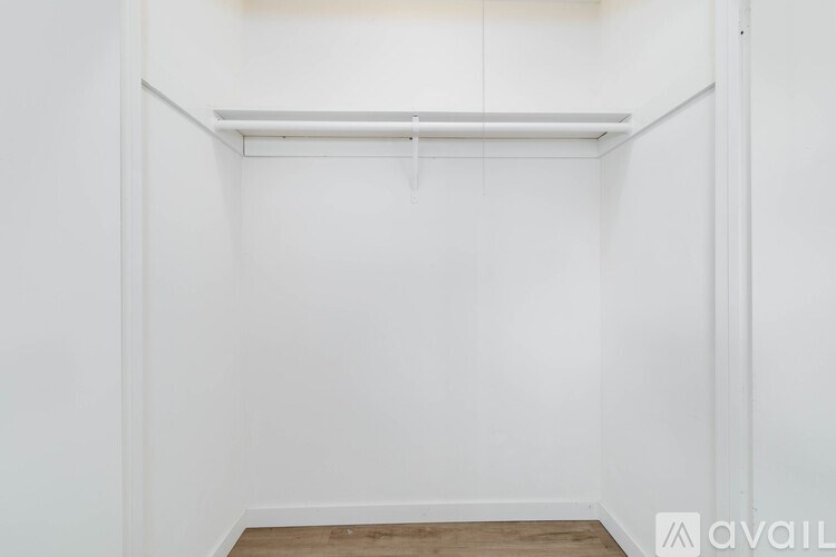 A white room with a wooden floor and a white wall.