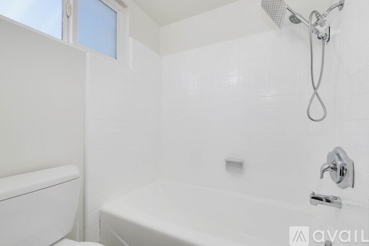 A white bathroom with a toilet, bathtub, and shower head.