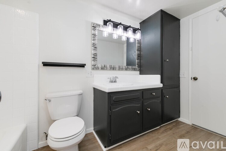 A bathroom with a white toilet, a white sink, and a black cabinet.