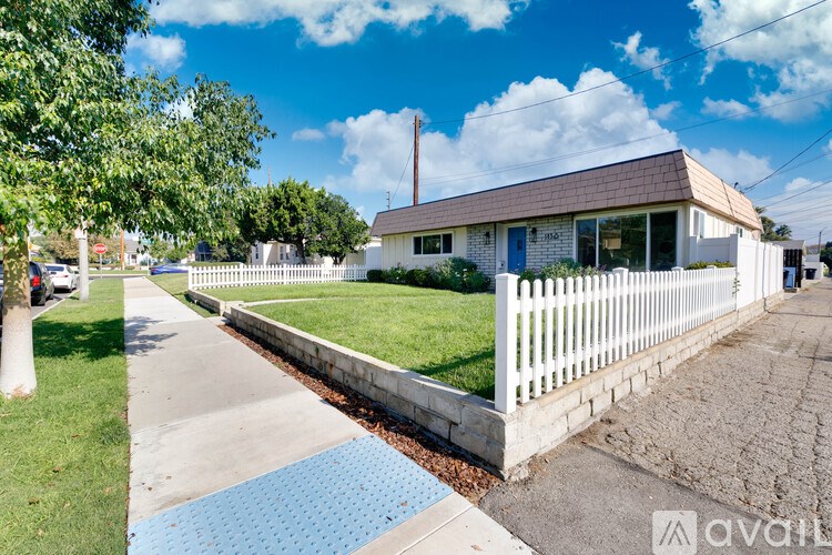 A house with a white picket fence and a blue roof is shown.