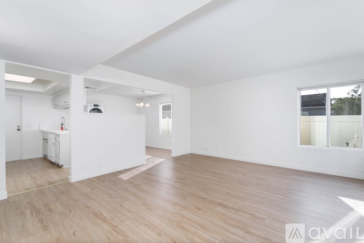 A spacious room with wooden flooring and white walls.