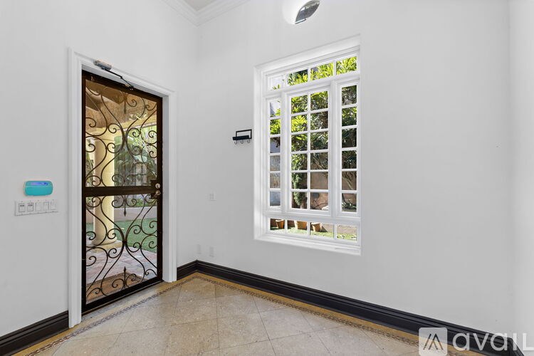 A hallway with a glass door and a window with a view of trees.