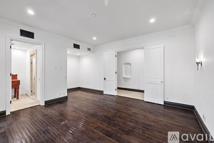 A room with wooden floors and white walls, with a chair and a table in the corner.