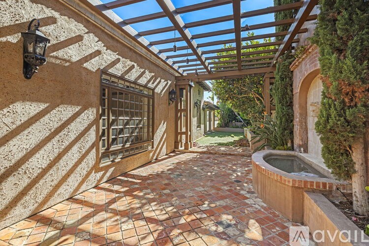 A patio with a hot tub and a wall with a window.