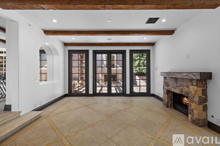 A large, empty room with a fireplace and a set of stairs leading to the upper floor.