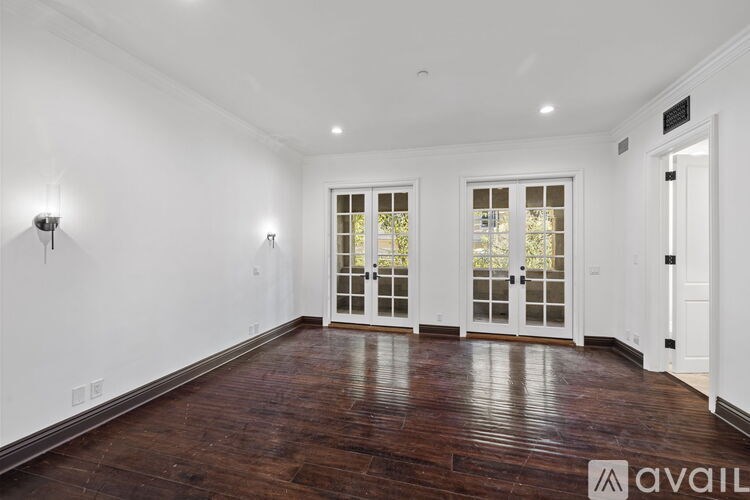 A room with wooden floors and white walls has a door with a glass panel.