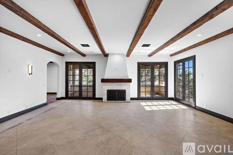 A spacious room with a fireplace and wooden beams on the ceiling.