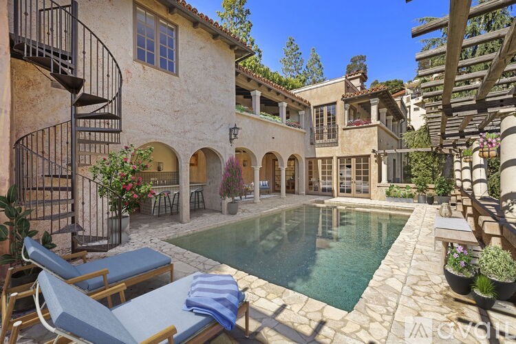 A pool surrounded by a patio with chairs and a table.