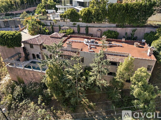 A large house with a red roof and a balcony surrounded by trees.