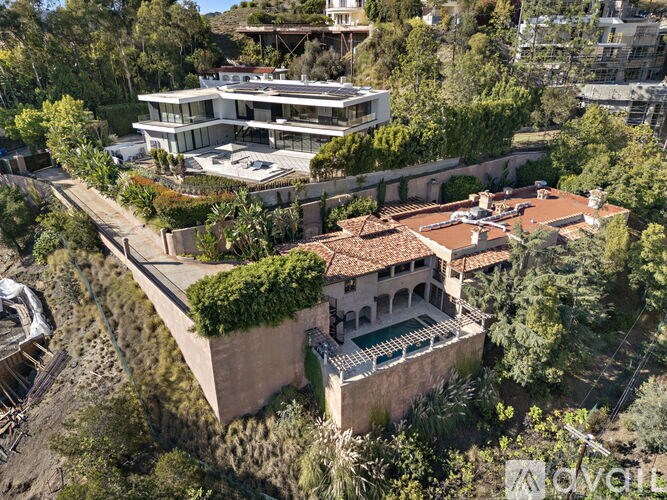 A modern house with a terrace is surrounded by greenery.