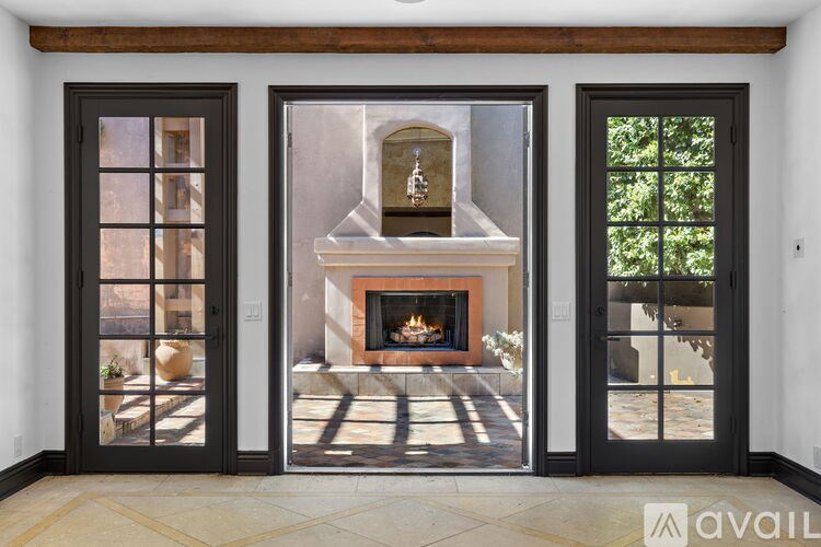 A modern interior with a fireplace and a view of the backyard through the glass doors.