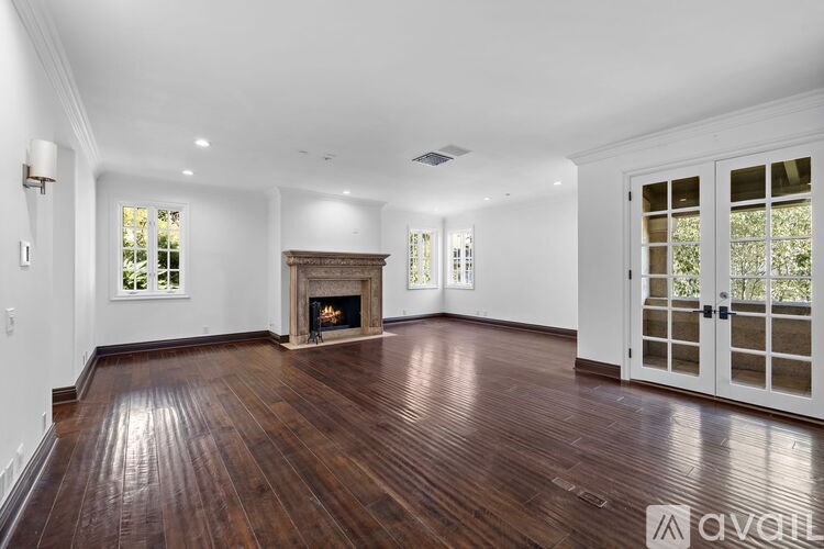 A spacious room with a fireplace and wooden floors.
