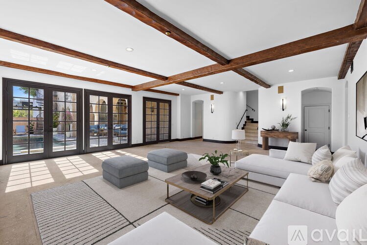 A spacious room with wooden beams on the ceiling and white walls.