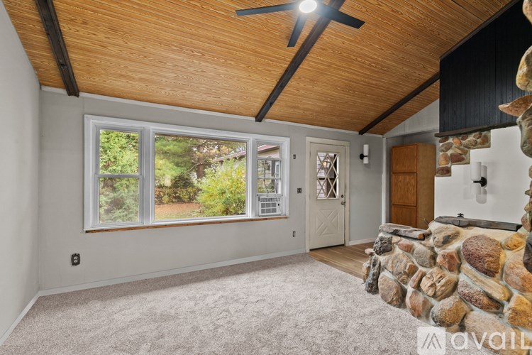 A room with a stone fireplace and a ceiling fan.