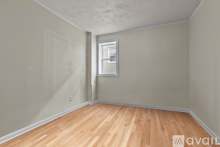 A room with wooden flooring and a window with blinds.