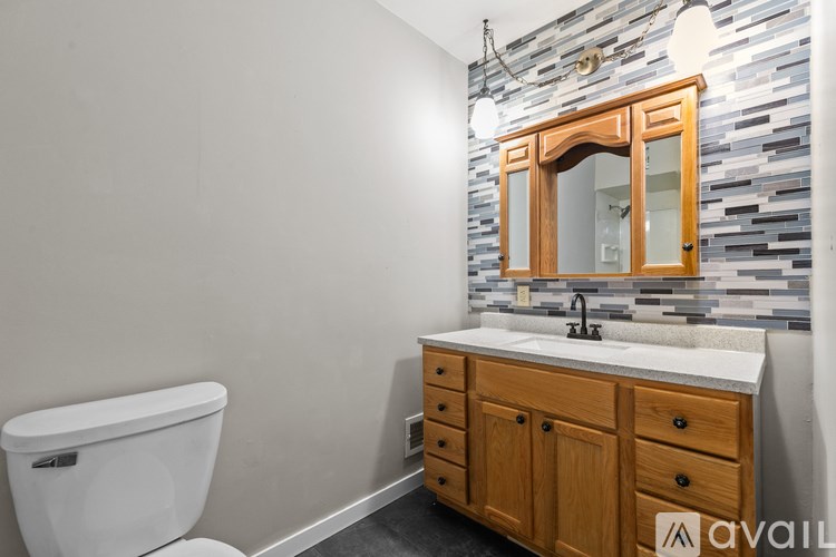 A bathroom with a toilet, sink and wooden cabinet.
