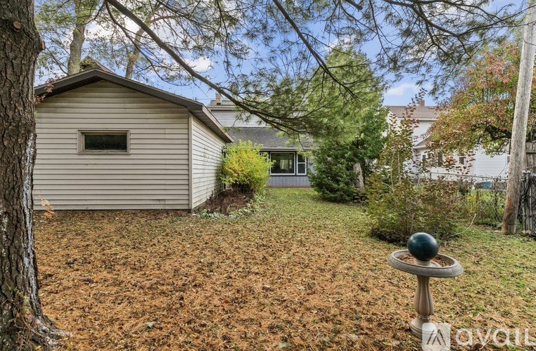 A small house with a window and a door is surrounded by trees and grass.