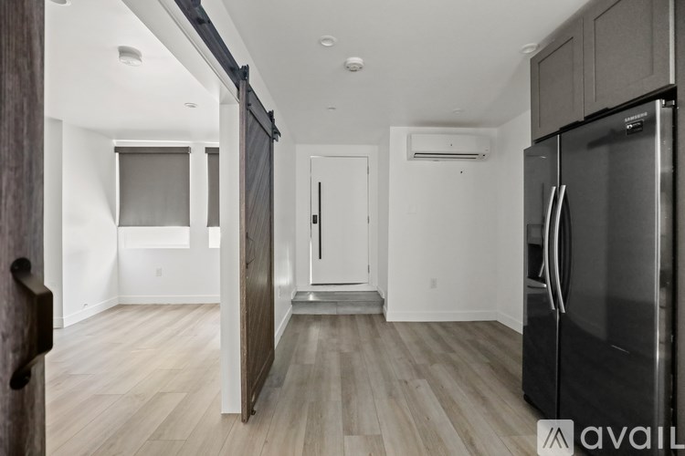 A kitchen with a black fridge and wooden floors.