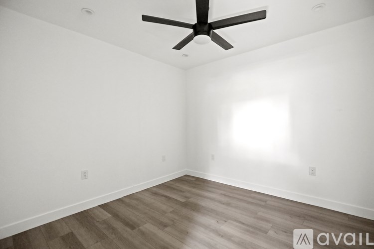 A room with a ceiling fan and wooden flooring.