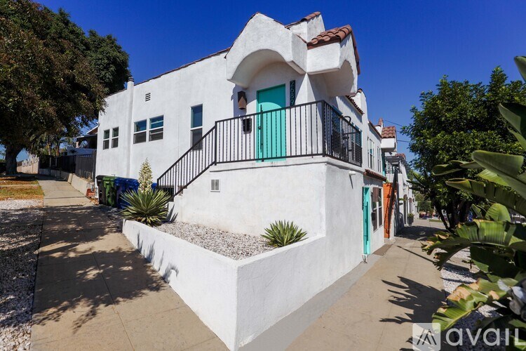 A white stucco house with a green door and a balcony.